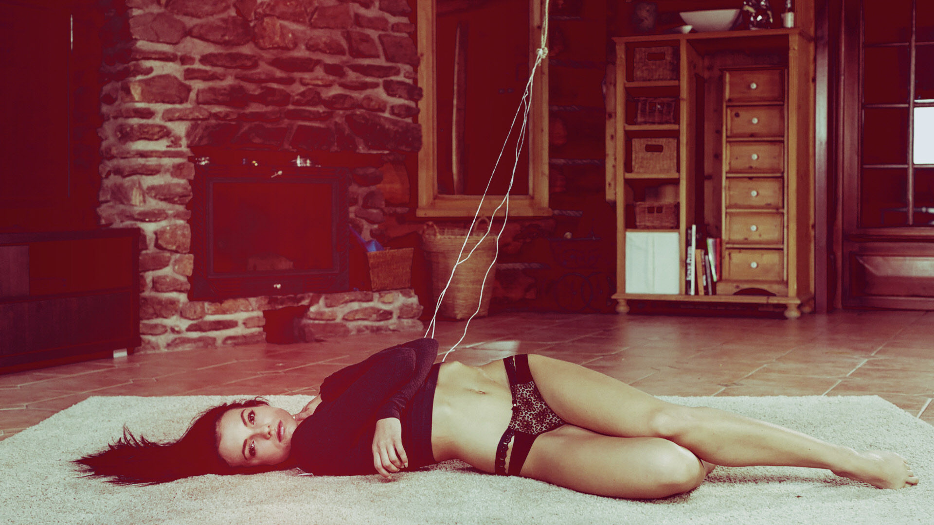 на полу лежит женщина с веревкой в руке