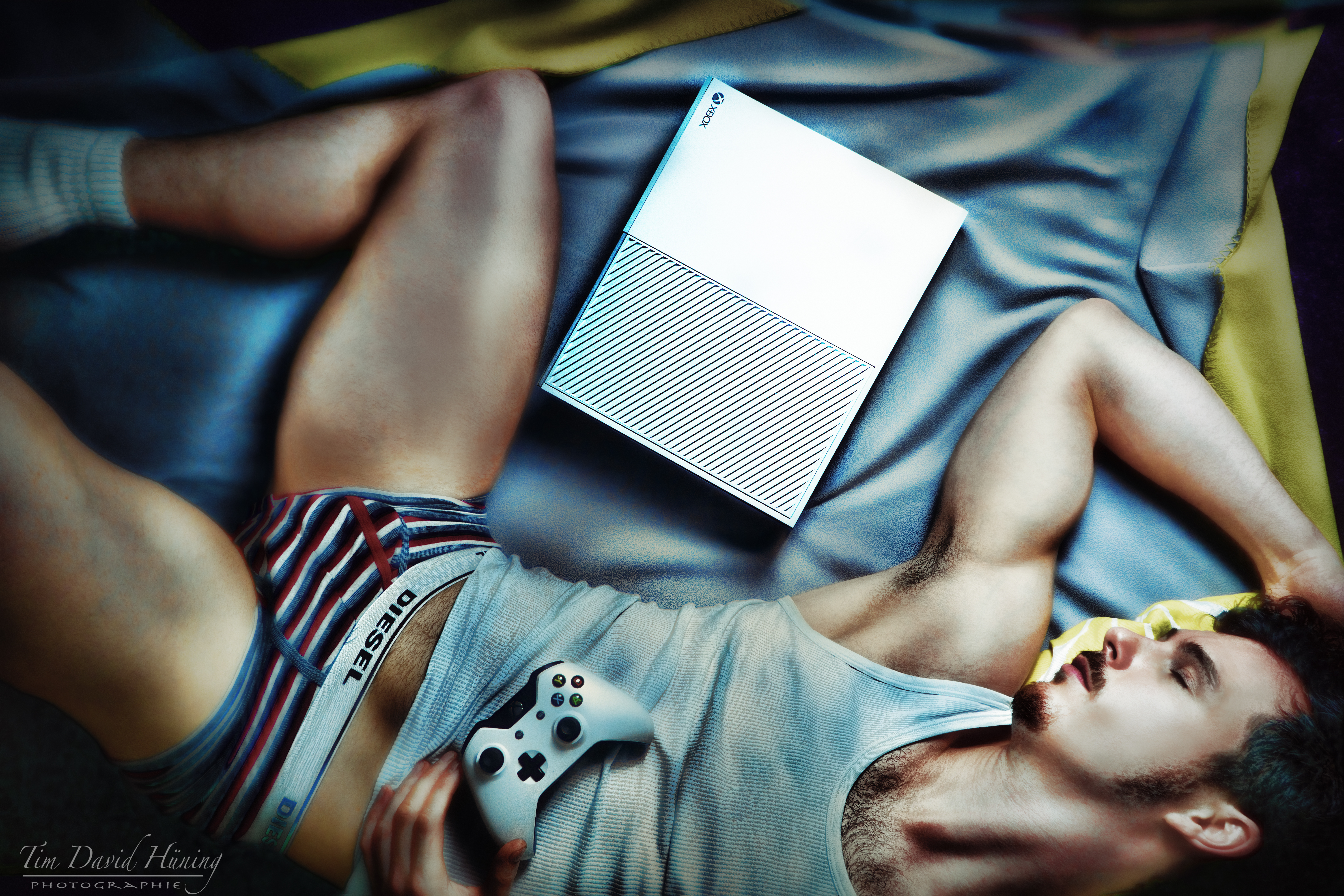 арафад лежал на кровати с игровым контроллером и ноутбуком