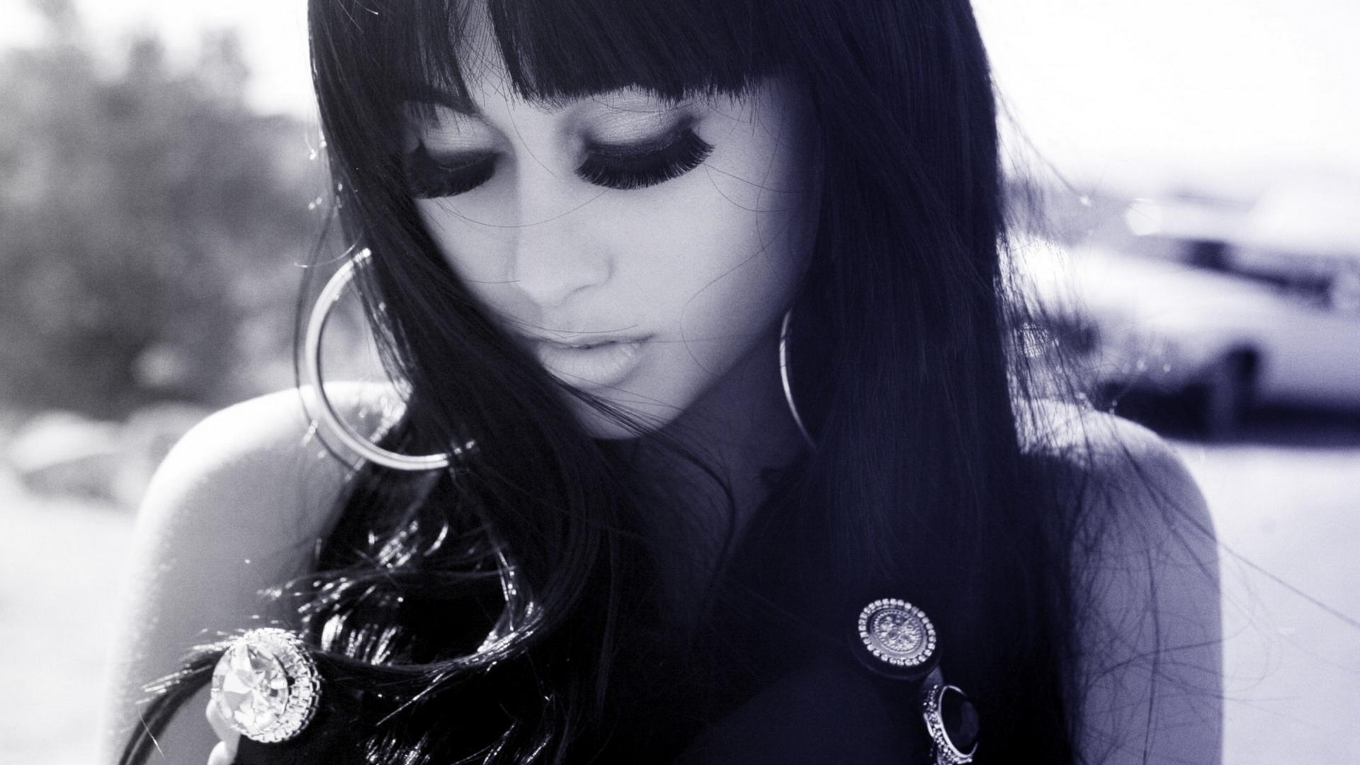 женщина с длинными черными волосами и серьгами смотрит вниз