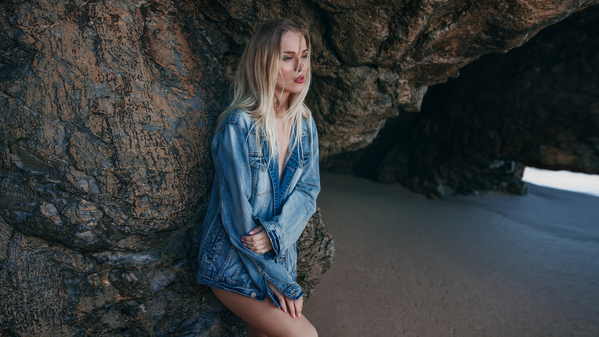 женщина, прислоненная к скале на пляже