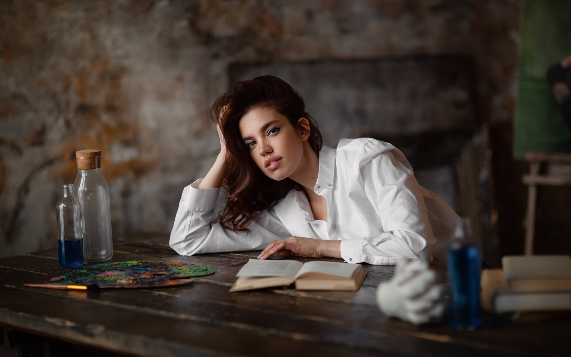 женщина сидит за столом с книгой и бутылкой