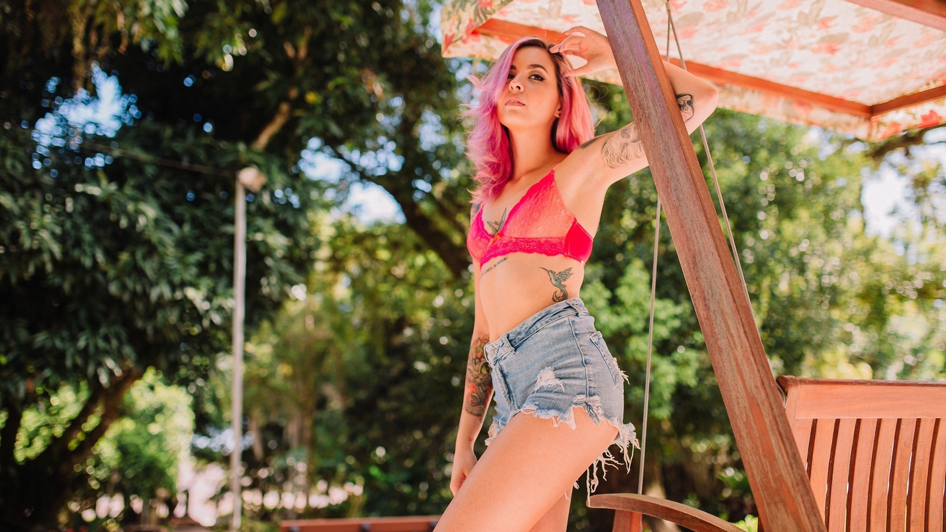 женщина с розовыми волосами и татуировками на качелях