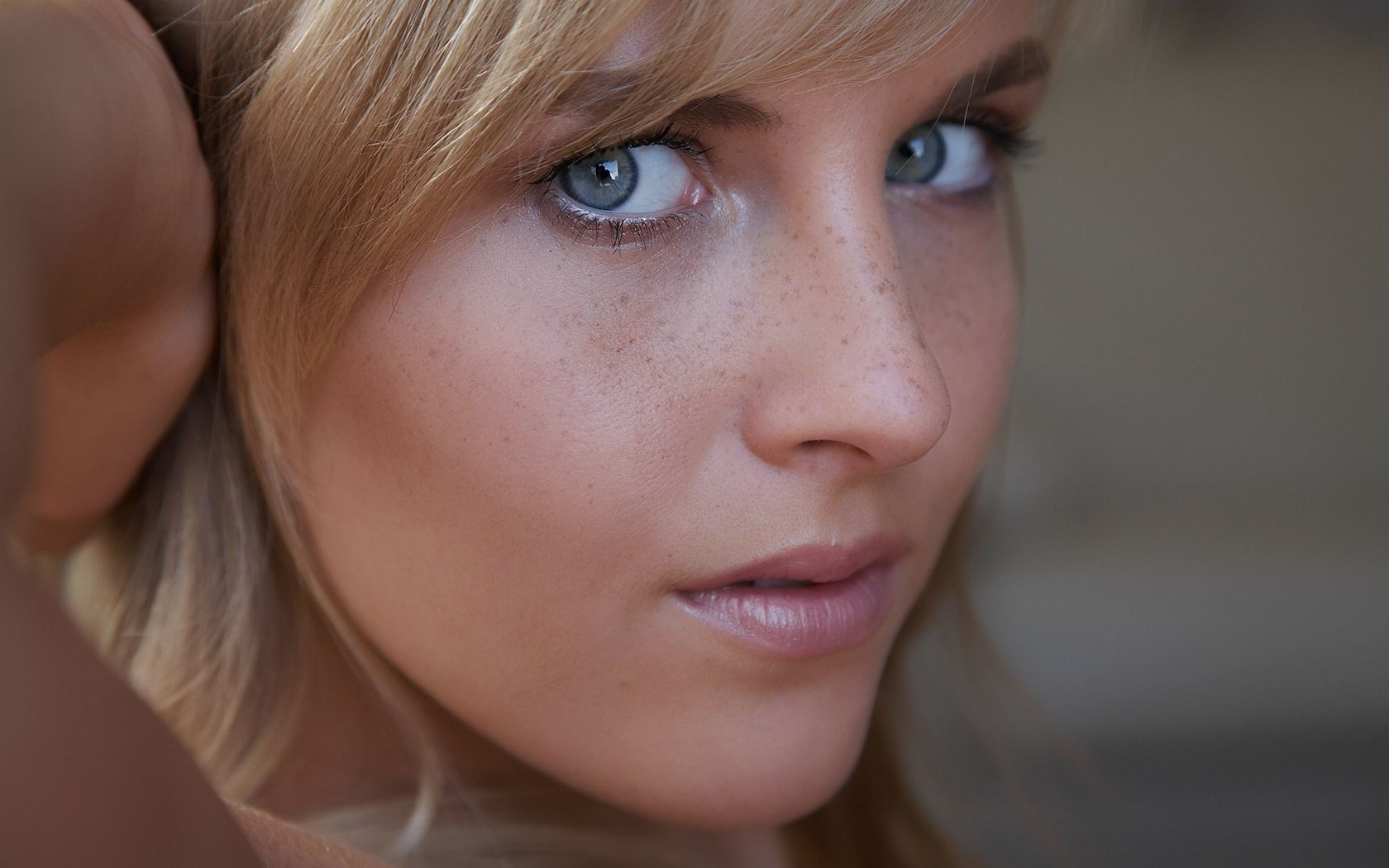 блондинка с голубыми глазами и веснушчатыми волосами смотрит в камеру