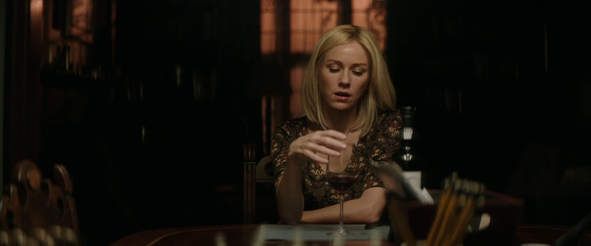 блондинка сидит за столиком с бокалом вина