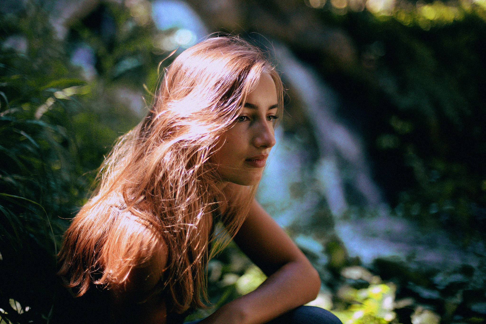 женщина сидит в траве возле водопада