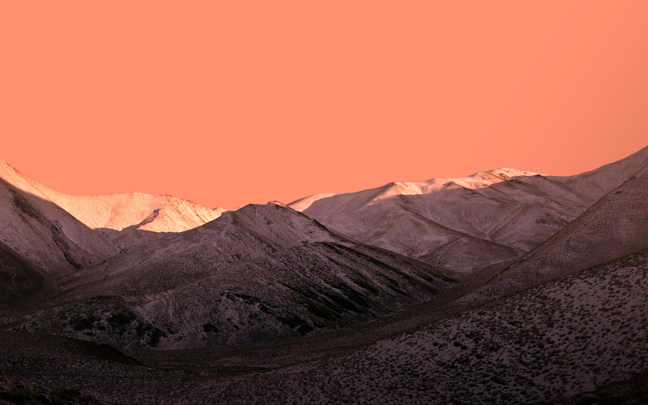 горы со снегом на них и розовым небом на заднем плане