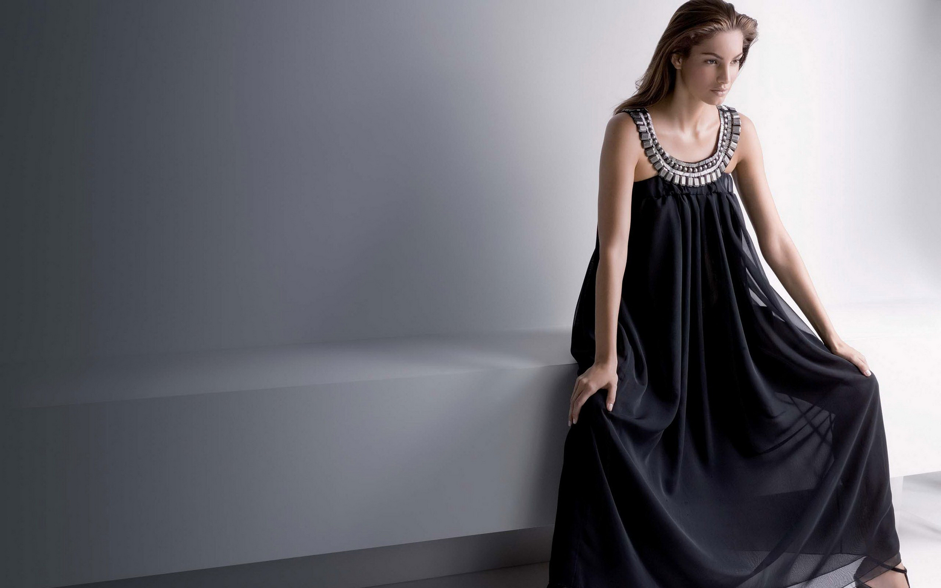 женщина в черном платье, прислонившись к стене