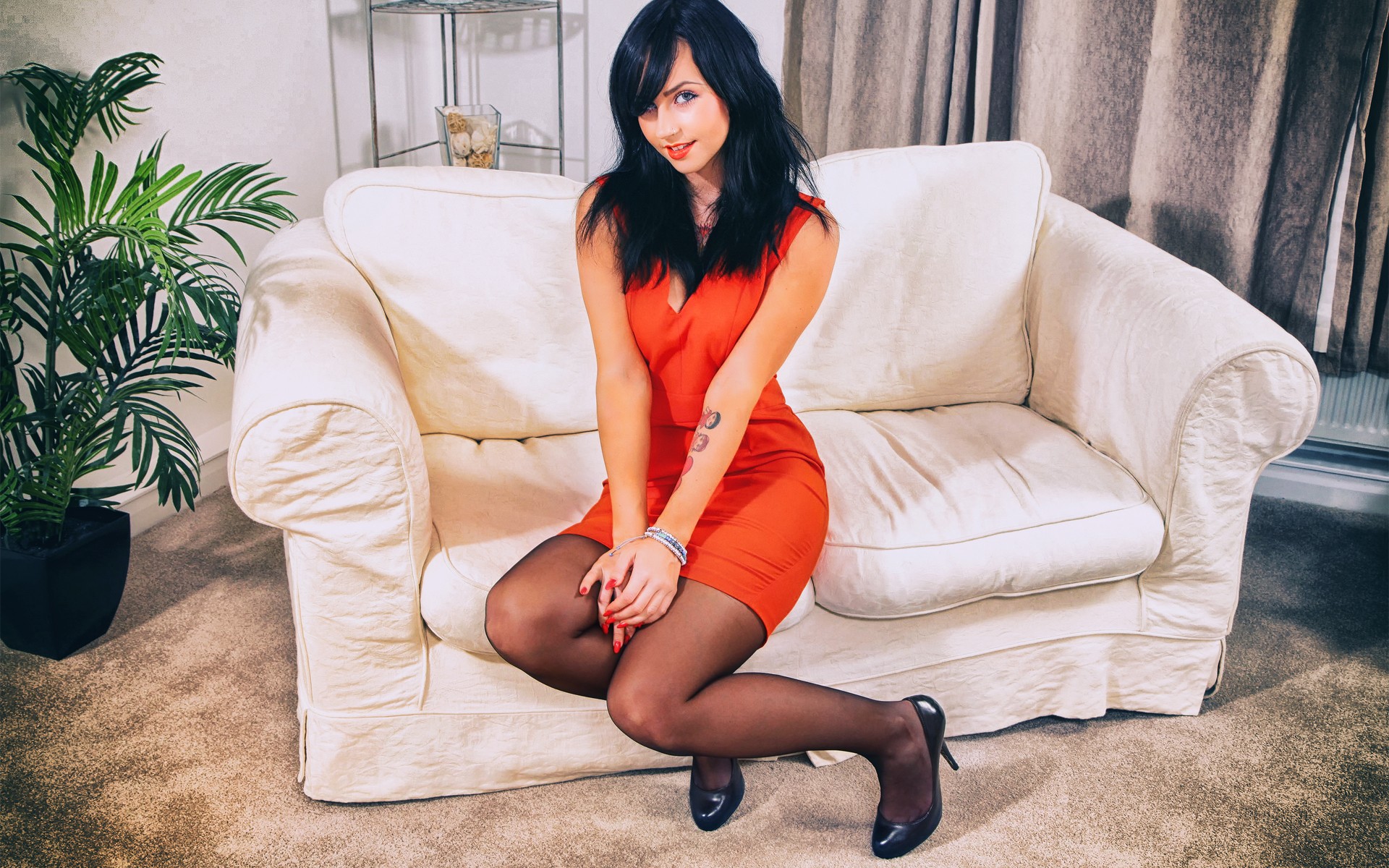 женщина сидит на диване в красном платье