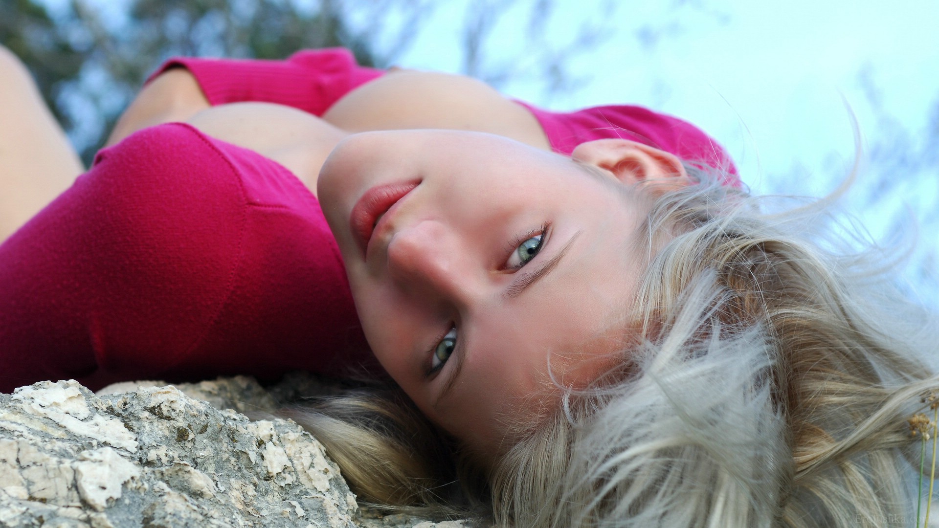 блондинка лежит на скале с закрытыми глазами