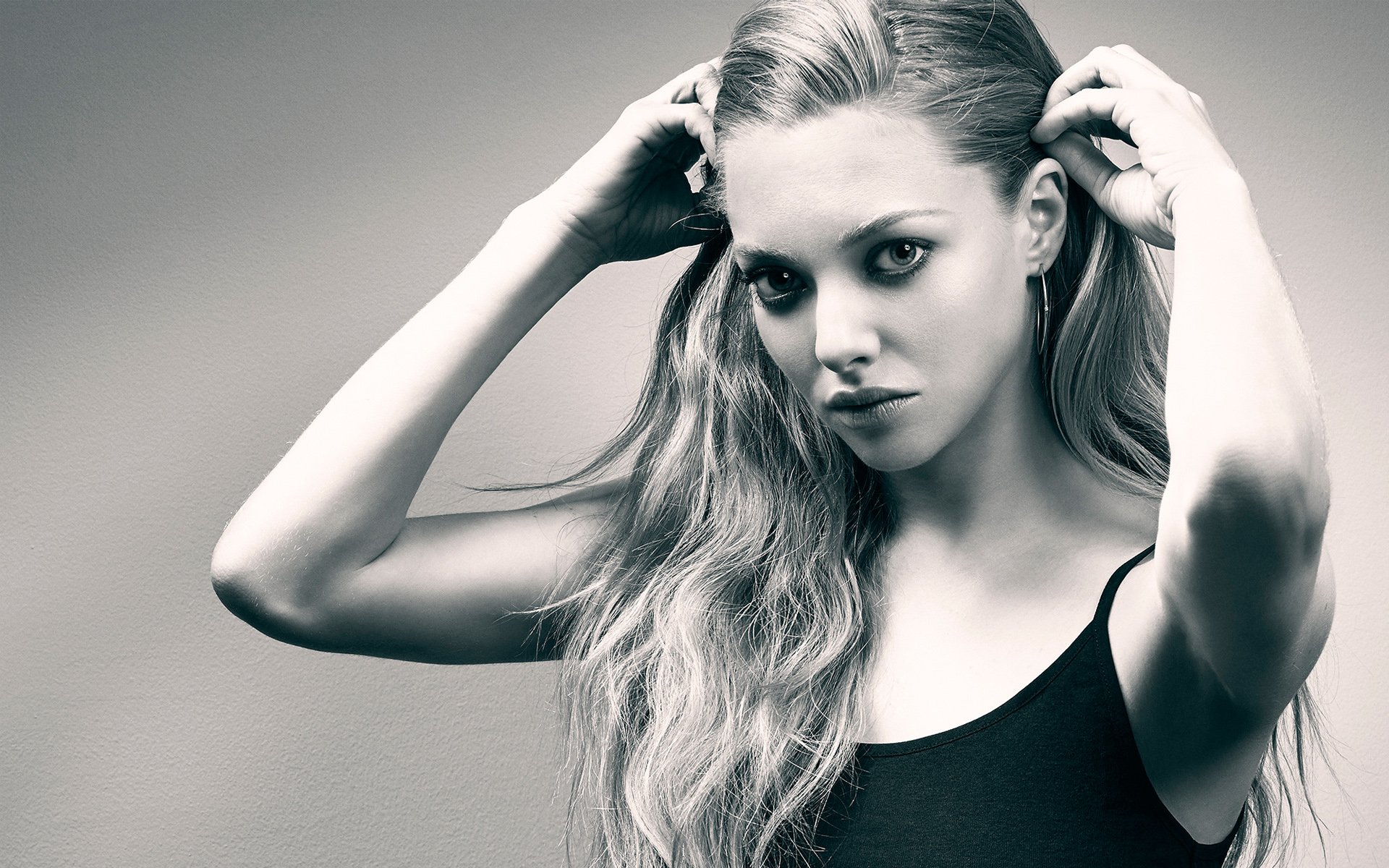 блондинка с длинными волосами в черном топе танка позирует для фото