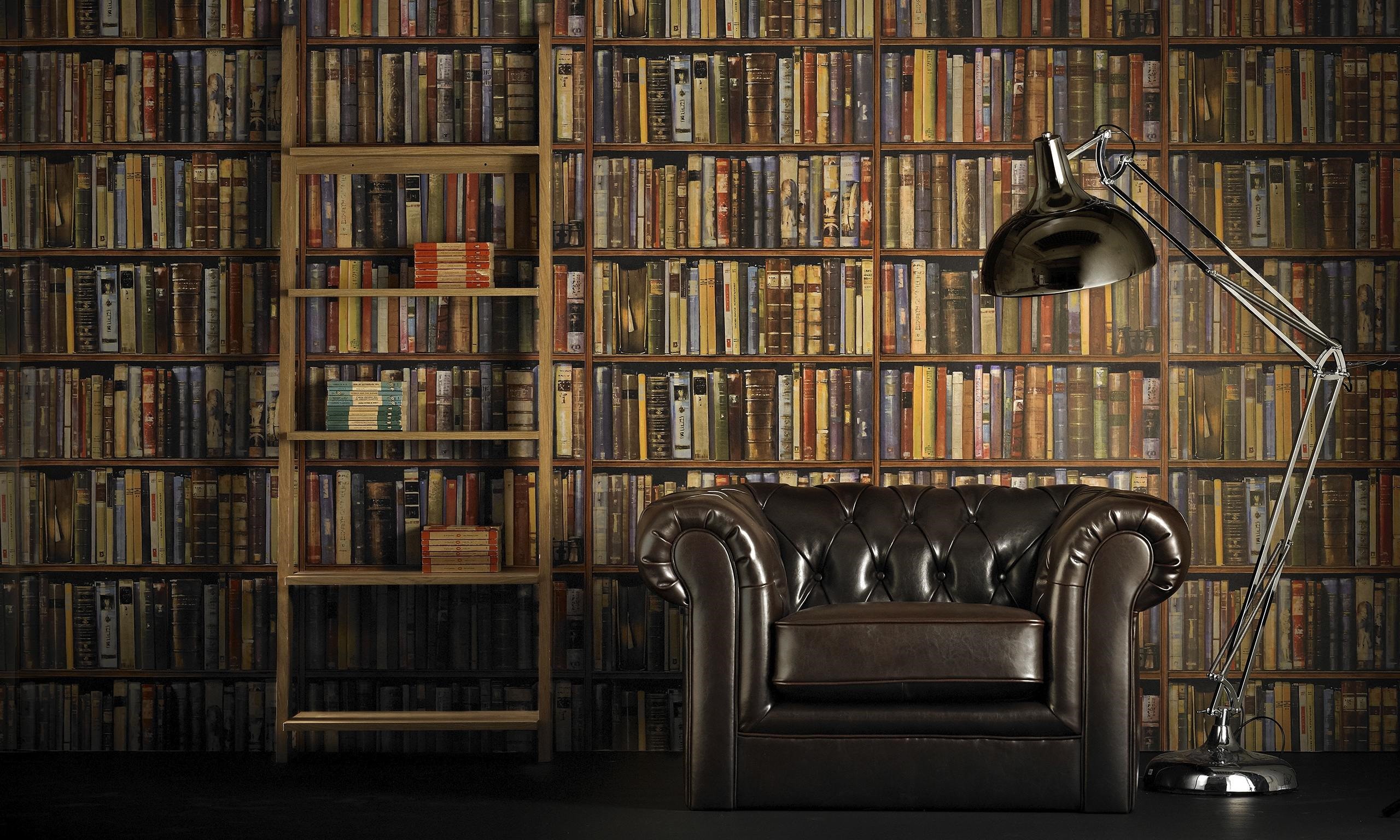 есть стул и лампа перед книжной полкой