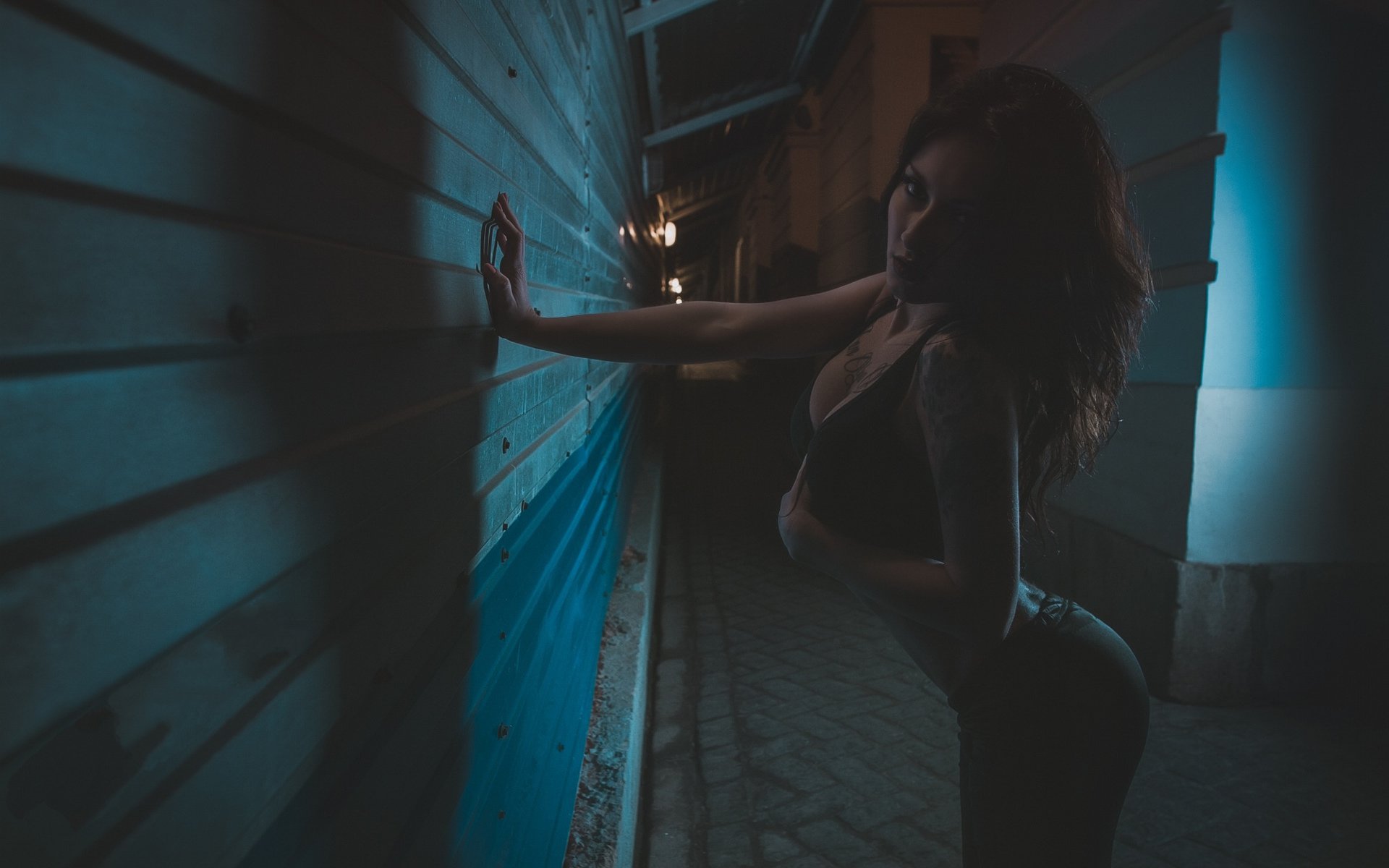 женщина, прислоненная к стене в темном переулке