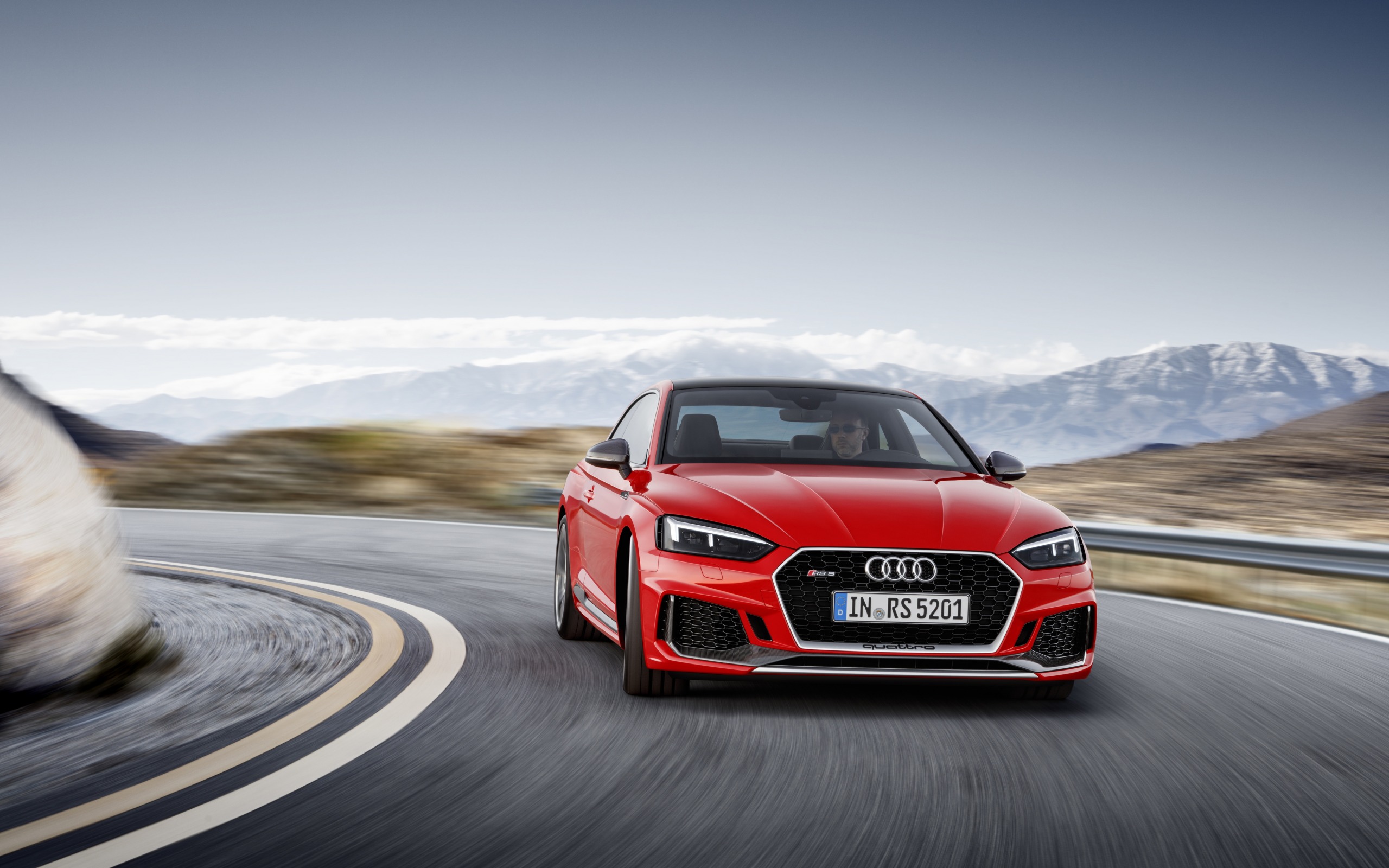 красный автомобиль audi, едущий по извилистой дороге с горами на заднем плане