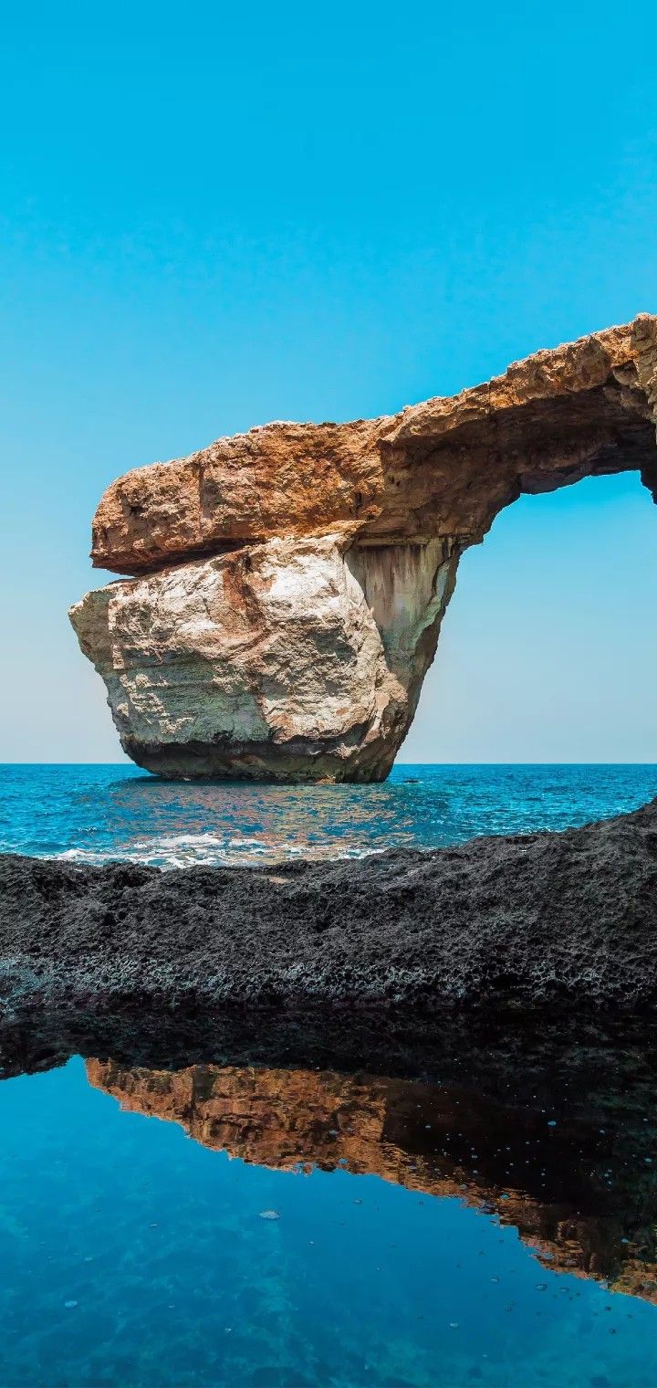 женское скалообразование посреди океана с отражением