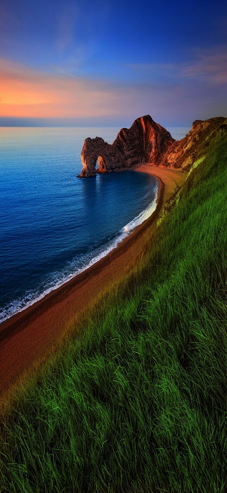 травянистый холм с видом на океан с пляжем и скальным образованием