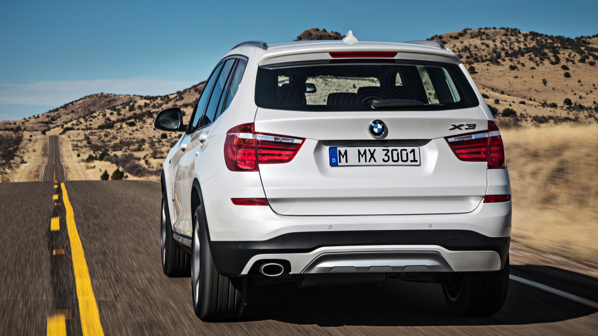закрытая крыша белого внедорожника bmw, едущего по дороге
