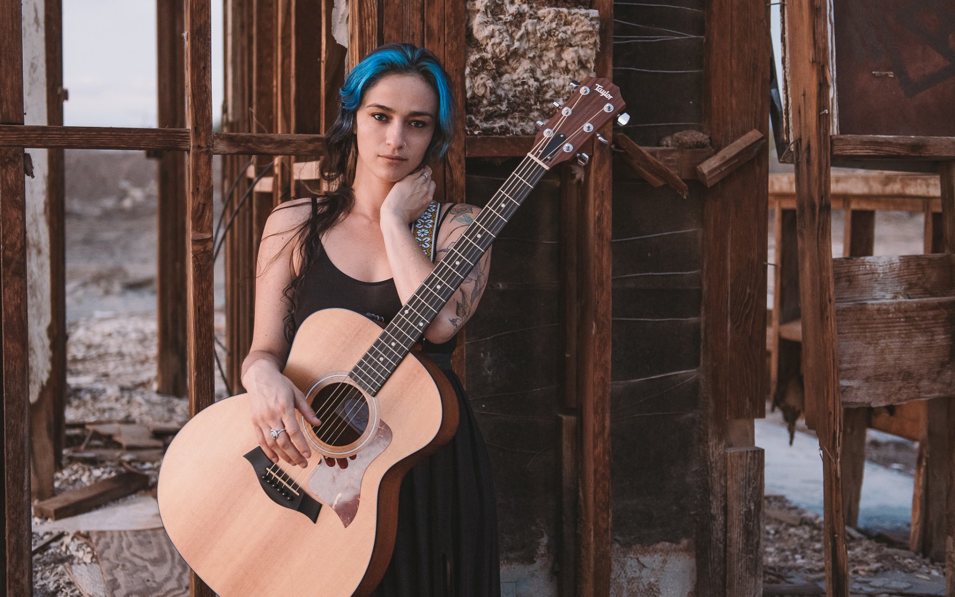 женщина с гитарой стоит перед зданием