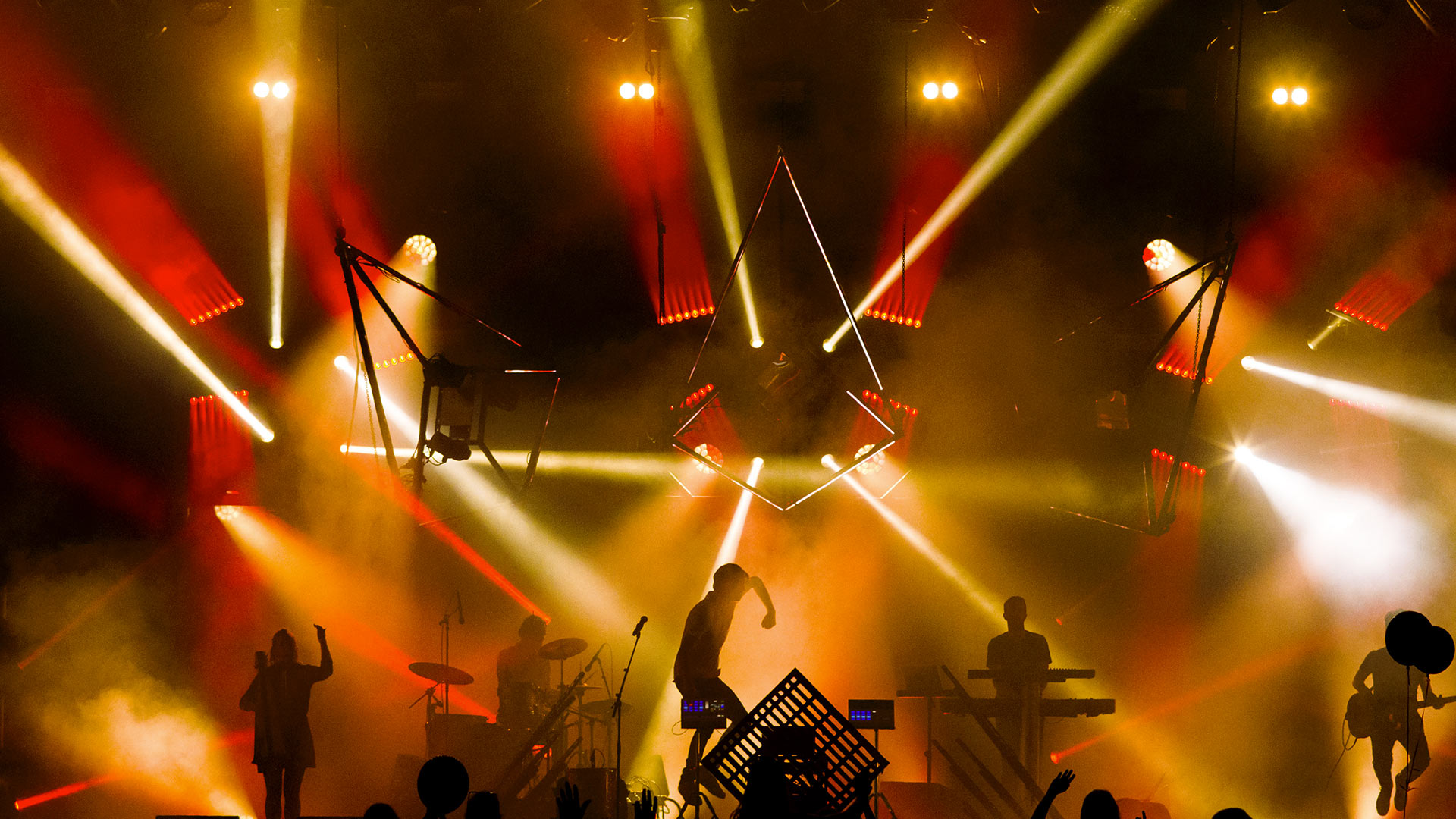 ярко освещенная сцена с группой, выступающей на сцене, и людьми, наблюдающими