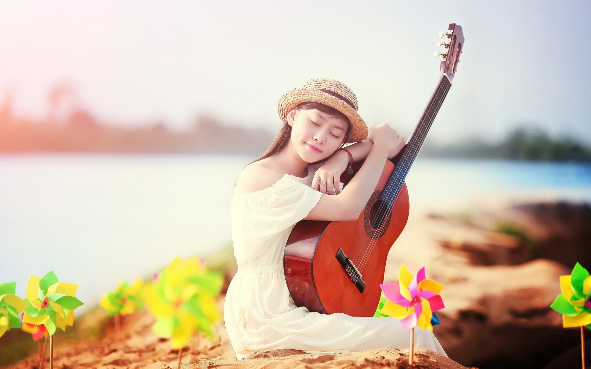 женщина в белом платье сидит на скале с гитарой