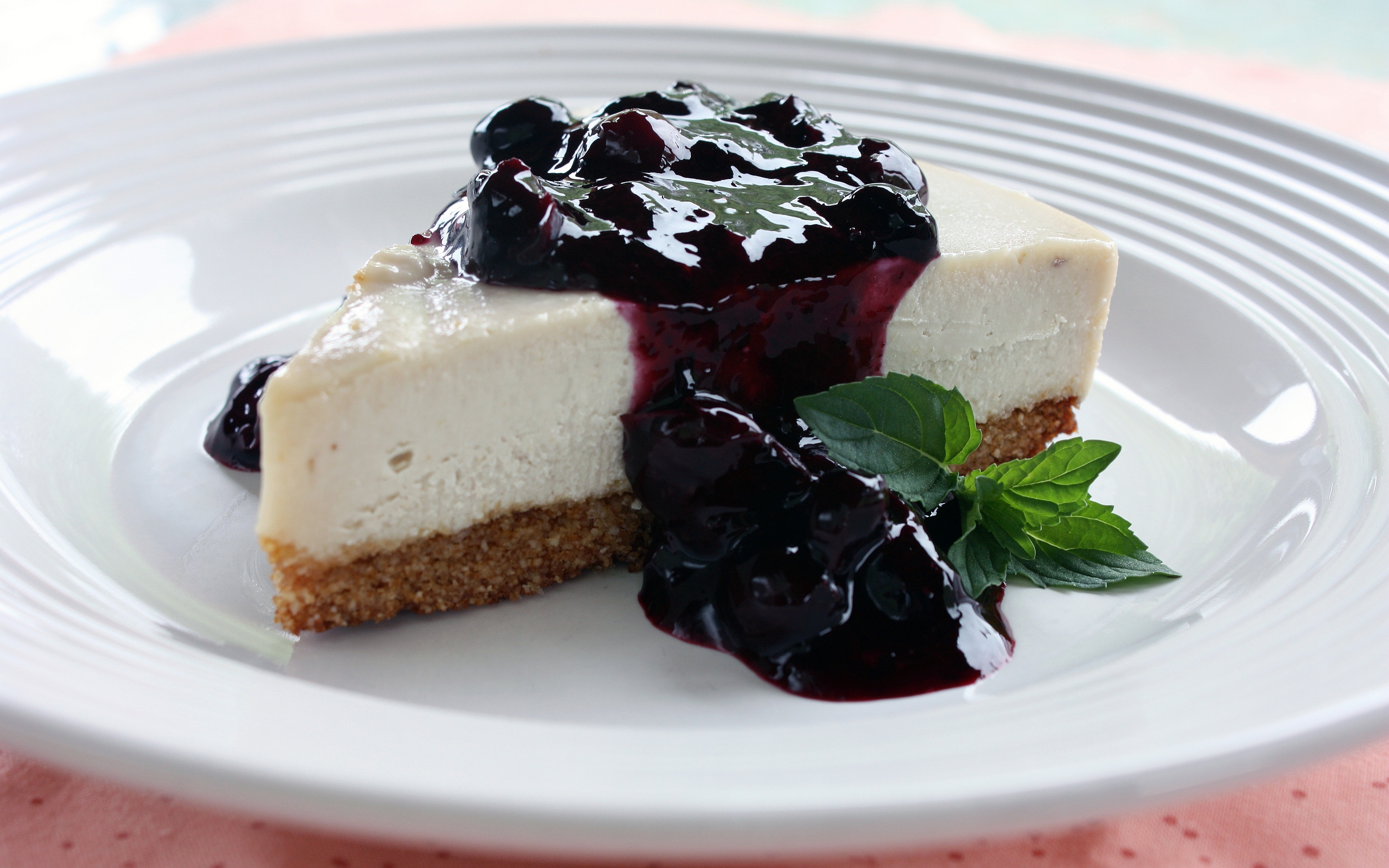 есть кусок чизкейка с черничным соусом на тарелке