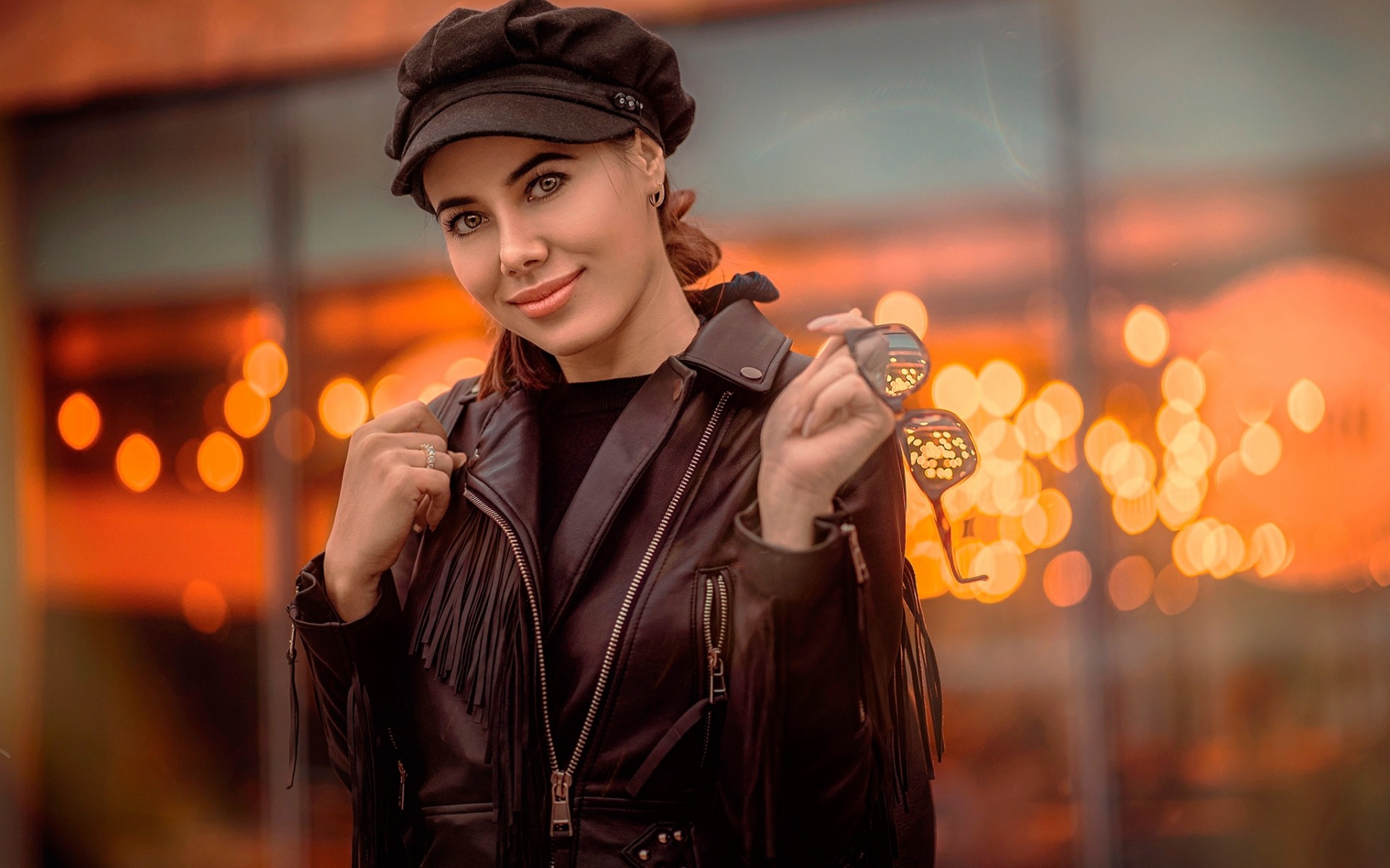 женщина в черной куртке и шляпе держит медаль