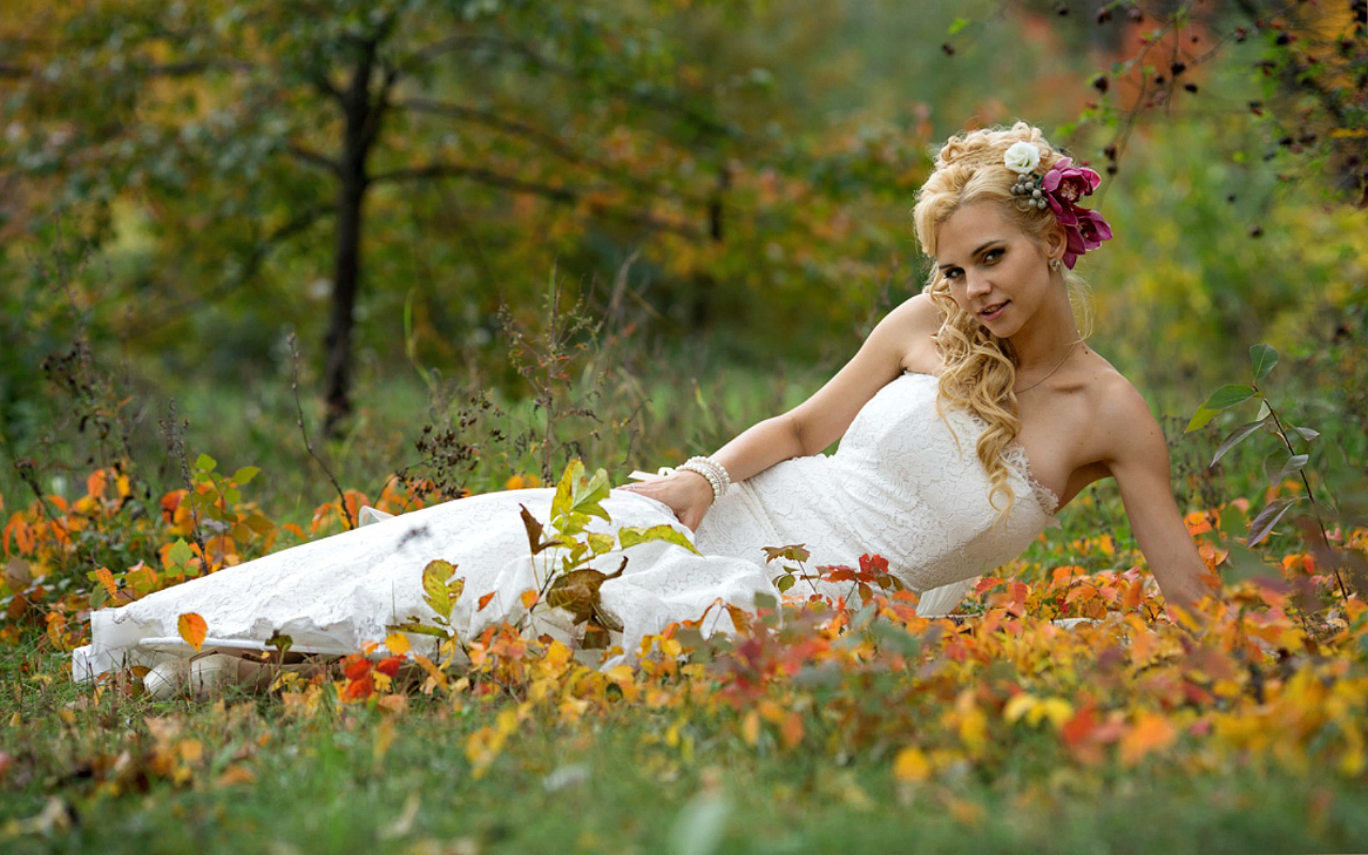 женщина в белом платье, лежащая в поле из листьев