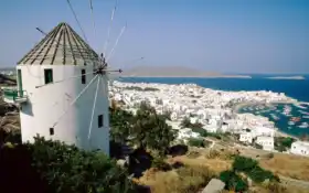 арафированная ветряная мельница на холме с видом на город и океан