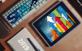 есть планшетный компьютер, сидящий на столе с клавиатурой и мышью