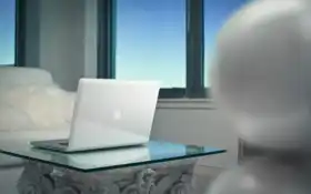 ноутбук на стеклянном столе перед окном