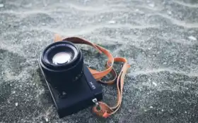 на земле лежит фотоаппарат, пристегнутый ремнем