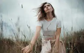 есть женщина, стоящая в поле высокой травы