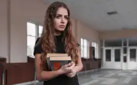 женщина держит книгу в коридоре со зданием на заднем плане