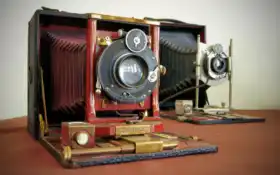 на столе есть небольшая деревянная камера с красной тканью