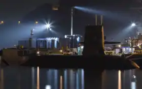 арафированная подводная лодка пристыковалась в гавани ночью с включенными огнями